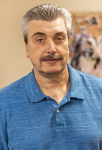 Portrait of a man with a mustache in a blue polo shirt